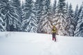 Man in goggles and snowshoes on the edge of pine forest