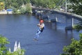 Man going down the zipline taking picture with mobile phone, Truhanov island and Pedestrian bridge on a background