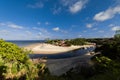 A man going to the edge of a cliff, where one can see the beach and some house. Royalty Free Stock Photo