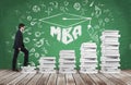 A man is going up using a stairs which are made of white books to reach graduation hat. The written word MBA is drawn on the green