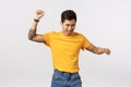 Man going wild, having fun and enjoying life. Attractive asian hipster guy in yellow t-shirt, tattooed, raising hands