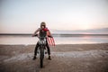 Man in golden helmet and american flag cape driving motorcycle Royalty Free Stock Photo