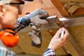 Man in googles making a mark on metal frame on unfinished attic ceiling. Attic insulation and renovation