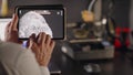 A man graphic designer holds in hands and uses a tablet to view 3d model of a human skull with teeth. The concept of