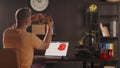 A man graphic designer holds plastic 3d printed model of human mandible. A sketch of heart in red colour on a laptop