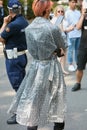 Man with gray and black raincoat with Fendi logos looking at smartphone before Fendi fashion show,