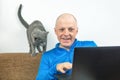 Man with a gray cat looks at a laptop screen. freelancer business works at home. relationship with a cat