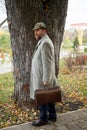 Man in gray coat stands in front of tree in park Royalty Free Stock Photo