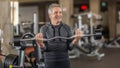 Man in gray hair pulling weights inside the gym Royalty Free Stock Photo