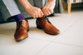 The man in gray slacks and a purple dress socks brown shoes with