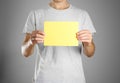 A man in a gray t-shirt holding blank clear yellow of the sheet.