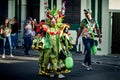 Man in green floral costume poses for photo on city street at dominican carnival