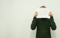 Man in a green jumper is standing and holding a white sheet of paper in his hands Royalty Free Stock Photo