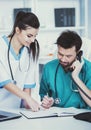 Man in green medical dressing gown speaks on phone.