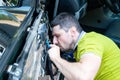 A man in a green t-shirt intently disassembles a car door in order to repair a power window. Car repair at a service station Royalty Free Stock Photo