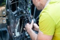 A man in a green t-shirt removes the door card to find a problem in the inoperative power window and repair it