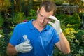 A man in a greenhouse examines a test tube with a liquid for fertilizing plants