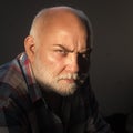 Man with grey beard, frown brows on serious face