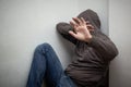 Man in grey hood sitting in the corner and hiding his face with the hands, show stop sign Royalty Free Stock Photo