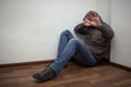 Man in grey hood sitting in the corner and hiding his face with the hands, show stop sign Royalty Free Stock Photo