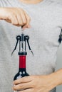 Man in grey shirt opening a red wine bottle Royalty Free Stock Photo