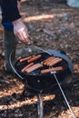 Man grill hot dogs in the forest