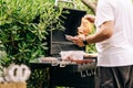 Man grilling meat on a barbecue various types of meat, chicken, sausages, blood sausage, lamb on a crbon grill in the garden