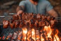 Man grills shish kebab over flames, sizzling with deliciousness