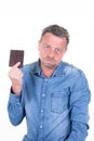 Man grimacing and blowing wearily with a bar of chocolate in his hand  isolated over white background Royalty Free Stock Photo