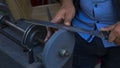 Man grinds down blade of knife with using a grinding machine on street Royalty Free Stock Photo