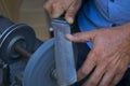 Man grinds down blade of knife with using a grinding machine on street Royalty Free Stock Photo