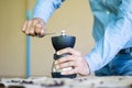 A man grinds coffee beans with a hand mixer