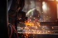 A man grinds metal. In the background a welder welds a part