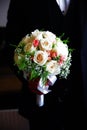 a man the groom in a black suit holds a bouquet of white roses in his hands. Royalty Free Stock Photo