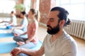 Man with group of people meditating at yoga studio