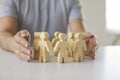 Man protecting wooden figures like corporate leader protecting team of his employees