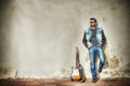 Man and guitar against a grungy wall in hdr Royalty Free Stock Photo