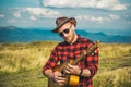 Man with guitar on nature. Hipster plays guitar on Camping holiday. Royalty Free Stock Photo