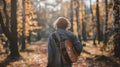 A man with a guitar slung over shoulder stands in the middle of a small clearing back to the camera as strums a tune