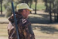 A man with a gun in his hands and an green vest  on a pheasant hunt in a wooded area in cloudy weather. Royalty Free Stock Photo