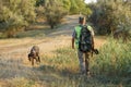 A hunter with a gun in his hands in hunting clothes in the autumn forest in search of a trophy.