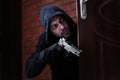 Man with gun spying behind open door. Criminal offence