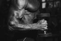 Man in gym. Muscular bodybuilder guy doing exercises with dumbbell. Strong person with Tense male hand with veins