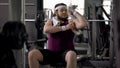 Man in gym pretending to be athletic, looking at biceps, workout motivation