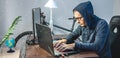 Hacker in a hood are programming virus code on a laptop. The concept of Internet fraud and personal data hacking Royalty Free Stock Photo