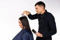 The man hairdresser cuts the long hair of the brunette woman. White background. Gender stereotypes