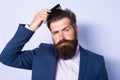 Man hairstyle, modern haircut. Man styling his hair with a comb. Bearded man with beard, bearded gay. Barbershop concept