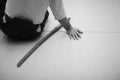 A man in hakama aikido sits on a mat