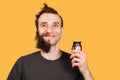 Man with half shave beard surprised with wide eyes hold hair clipper. Isolated on orange background