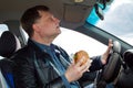 A man with a hamburger in his hand at the wheel Royalty Free Stock Photo